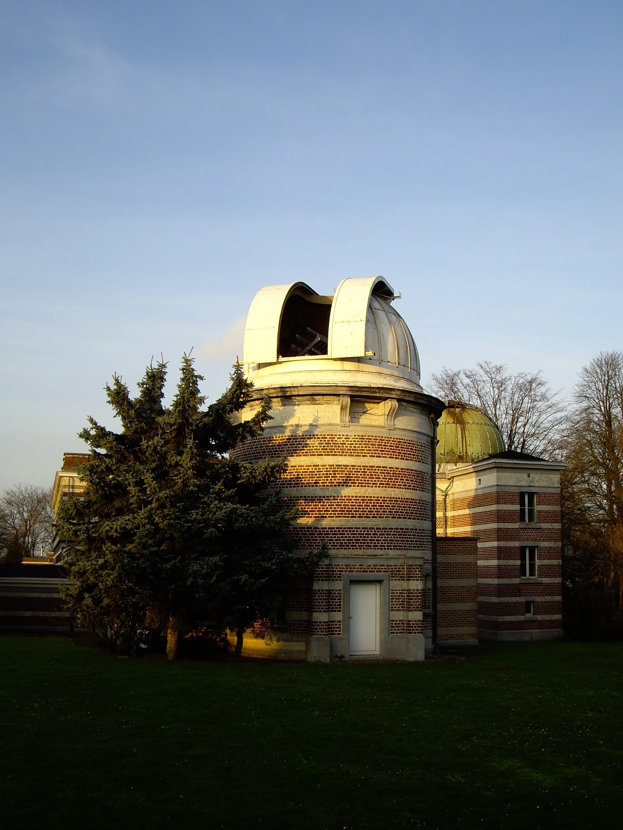 Dome-topped observatory building surrounded by trees under a clear sky.