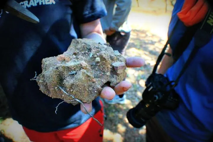 Soil science students observing a blocky aggregate in the field