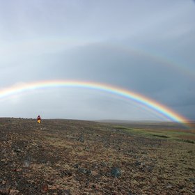 Field scientist under a spectacular rainbow