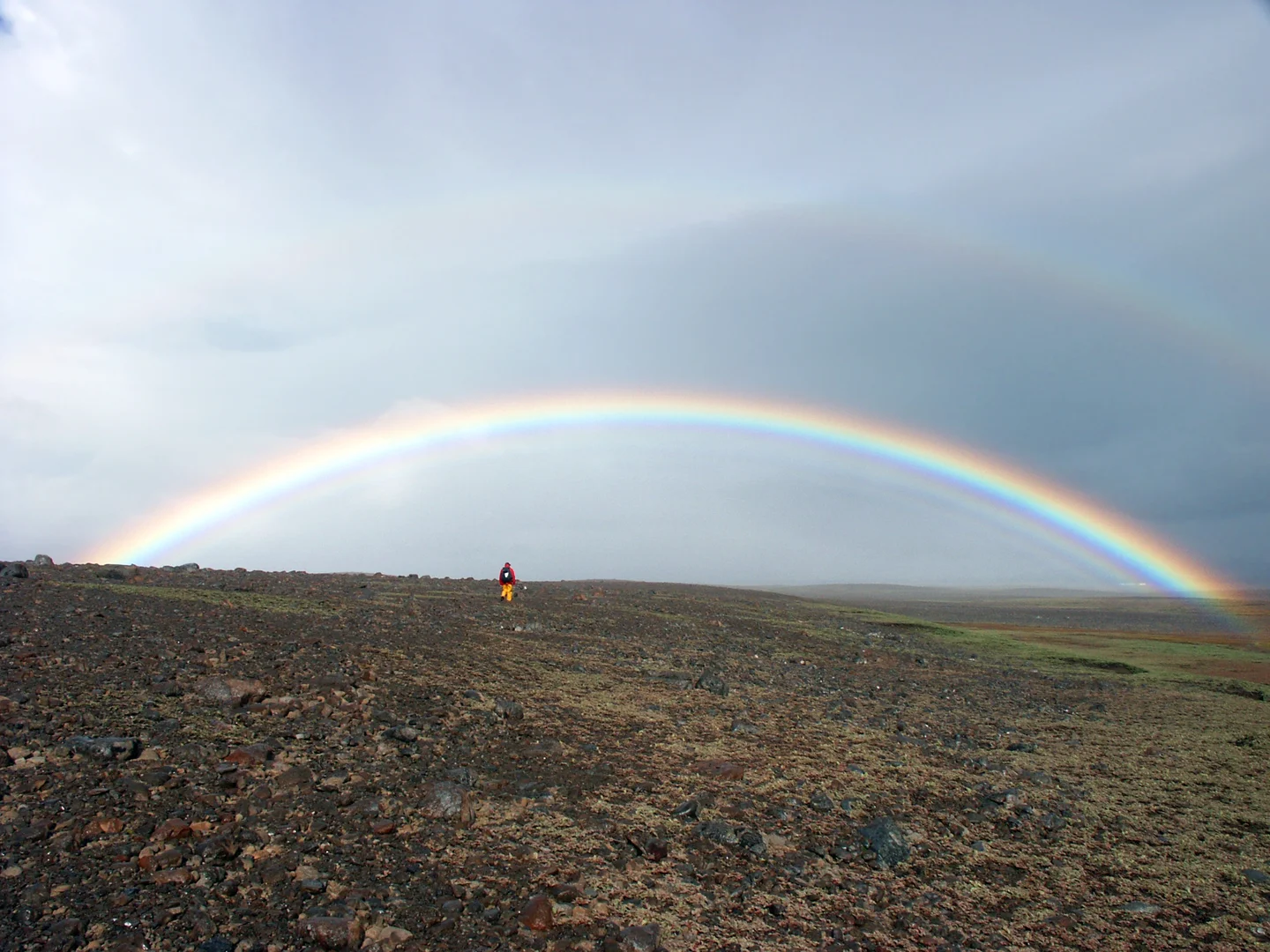 Field scientist under a spectacular rainbow