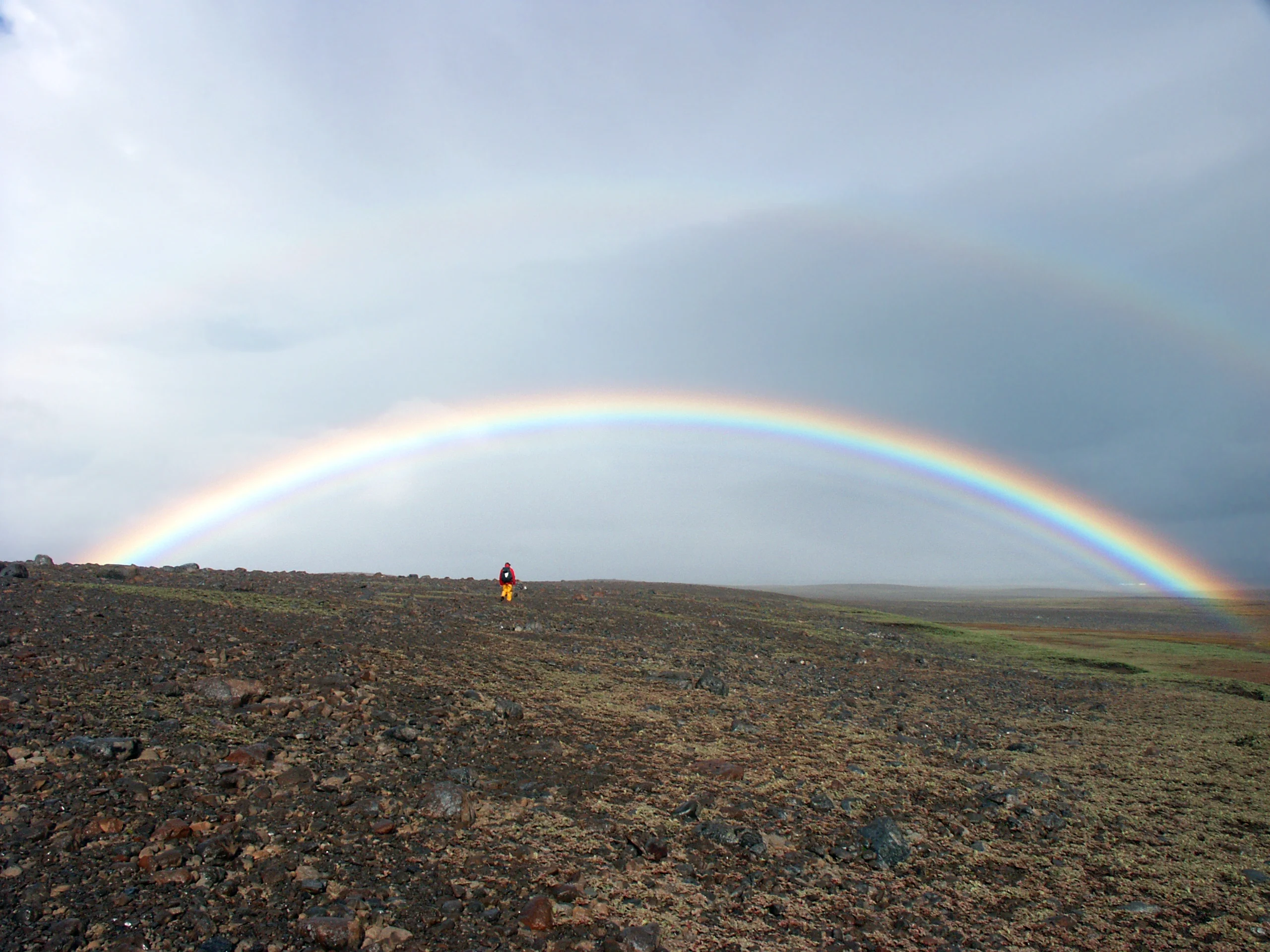 Field scientist under a spectacular rainbow