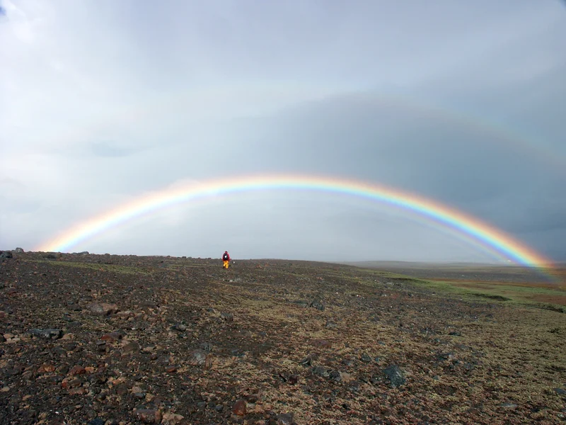 Field scientist under a spectacular rainbow