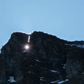 Aerosols become visible as the sun hides behind rock formation