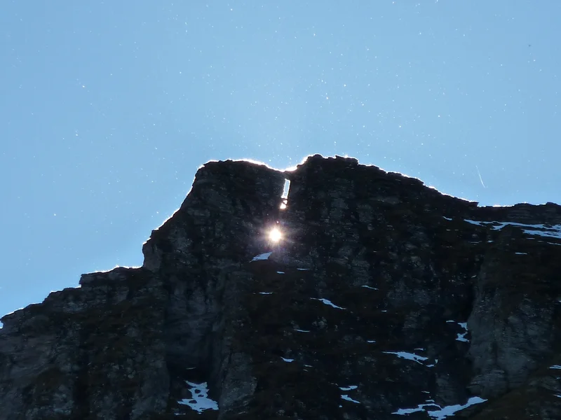 Aerosols become visible as the sun hides behind rock formation