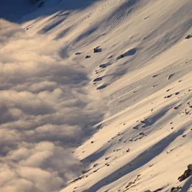 Clouds, snow and the sun on a mountain slope