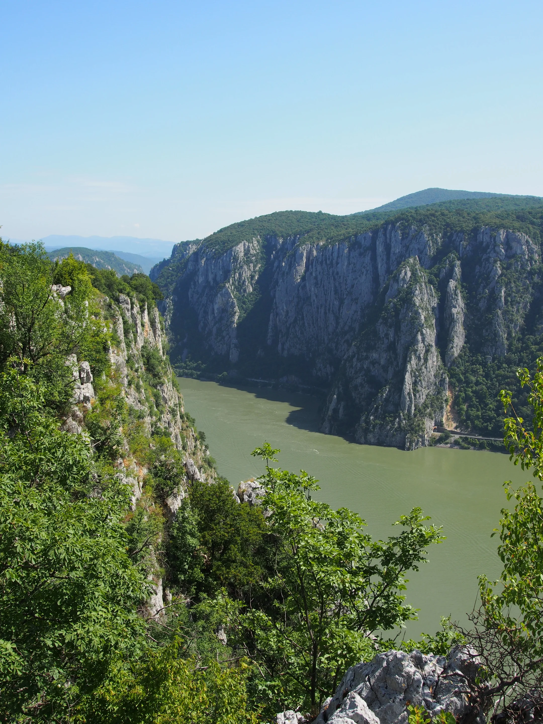 A winding river flows through a lush green canyon with steep, rocky cliffs.