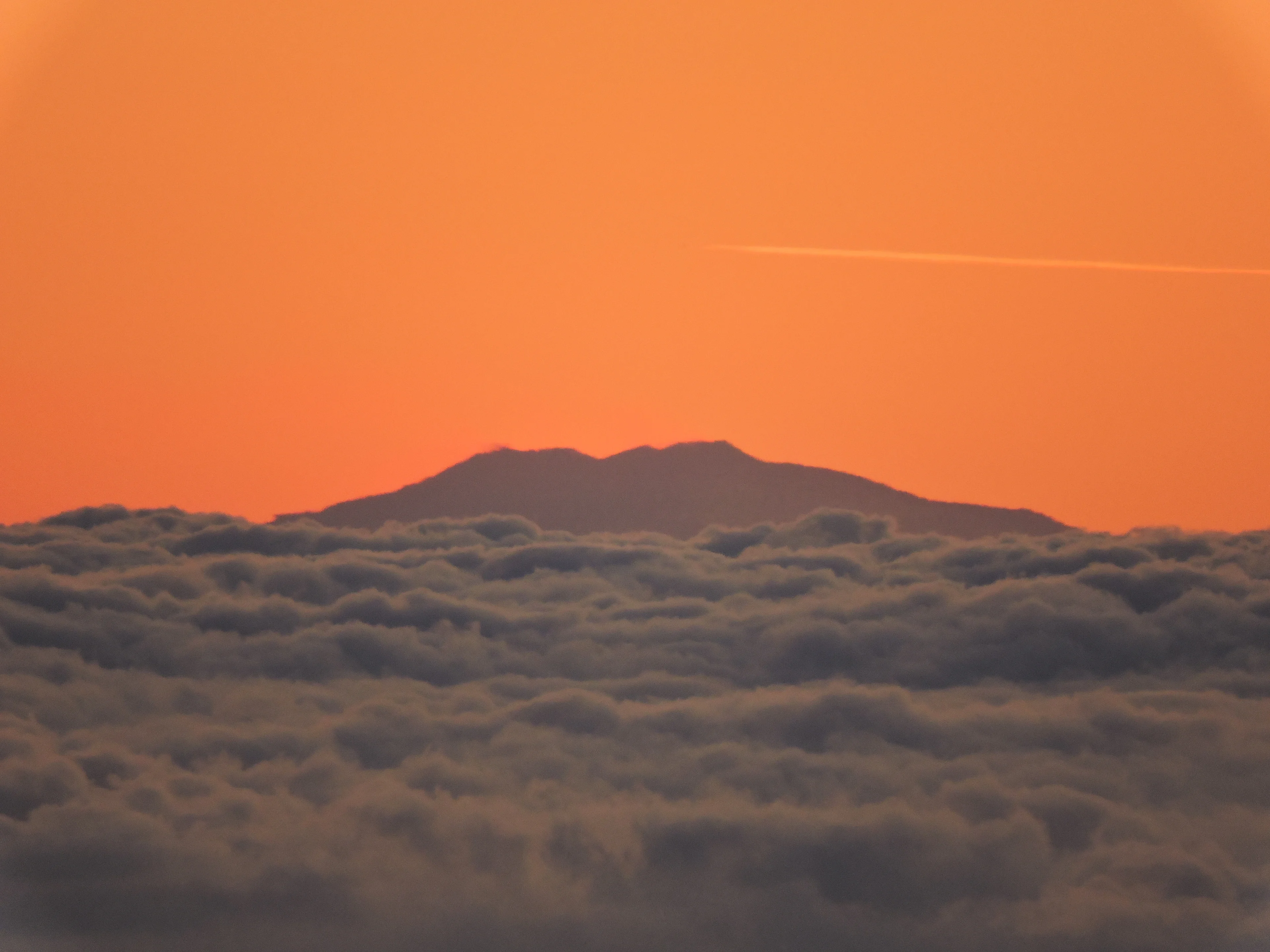 Summit of Mount Etna over a clouds carpet