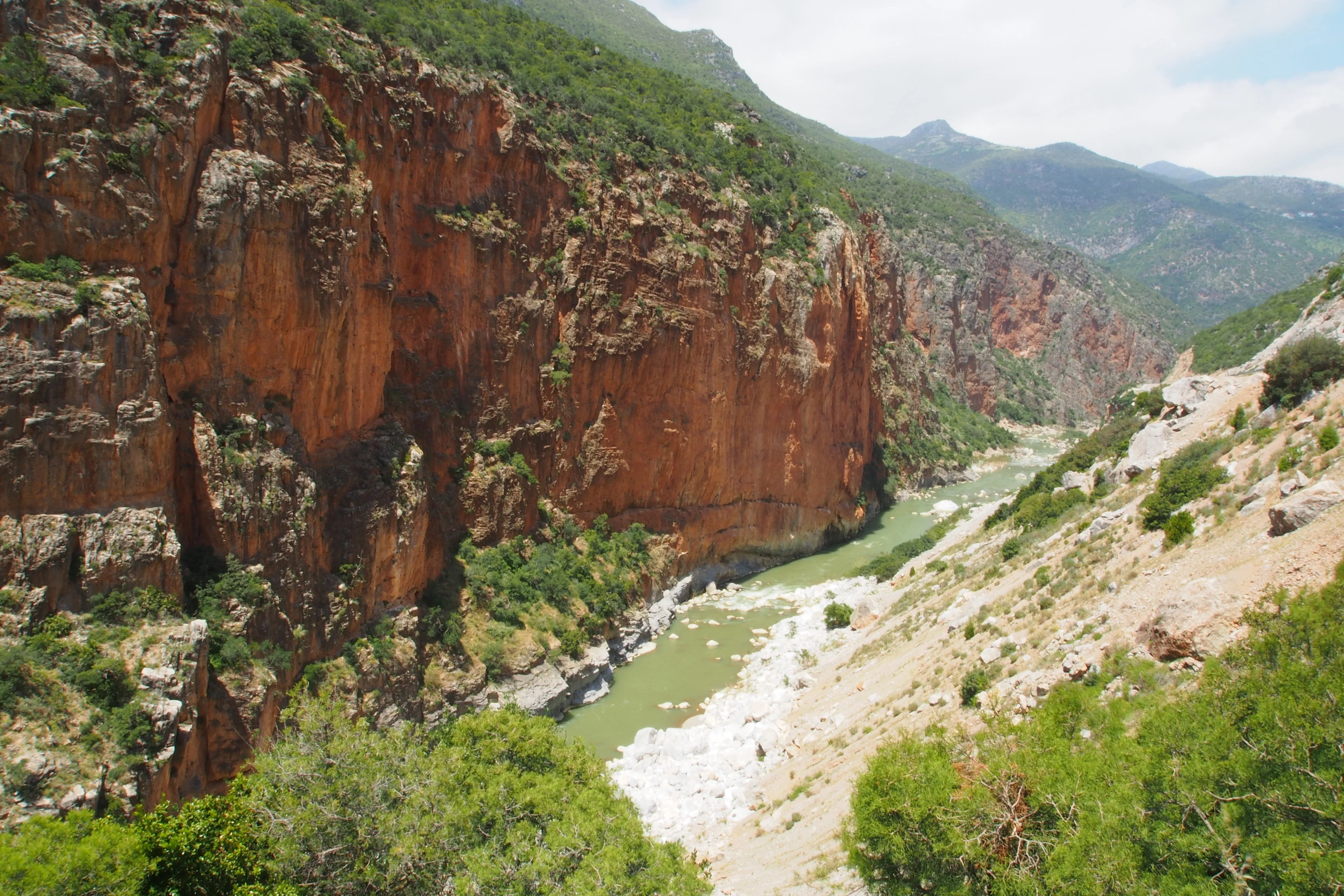 A winding river flows through a rugged, rocky canyon with lush greenery.