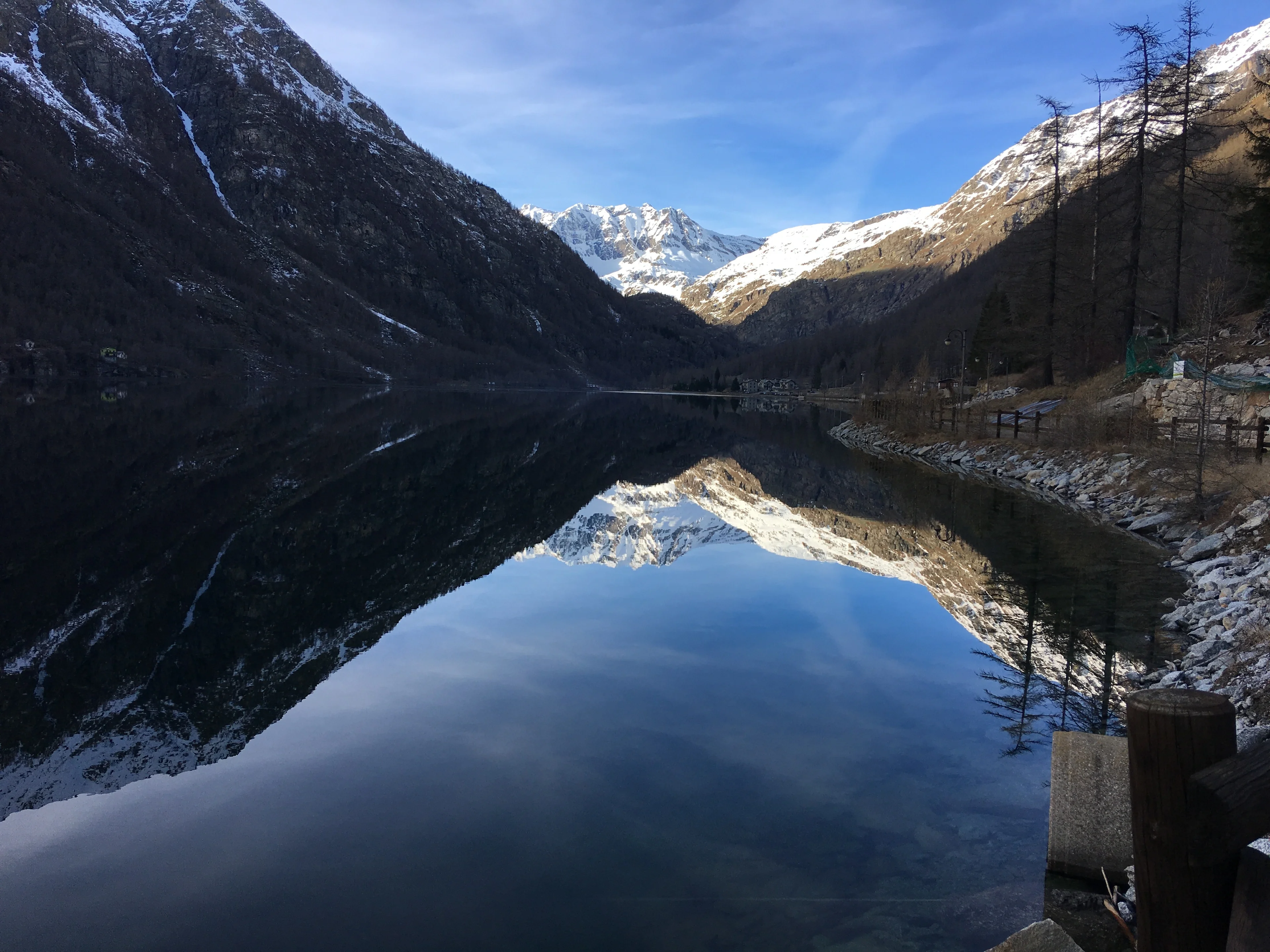 Ceresole Reale ice-free lake acting as a perfect mirror during sunny winter day.