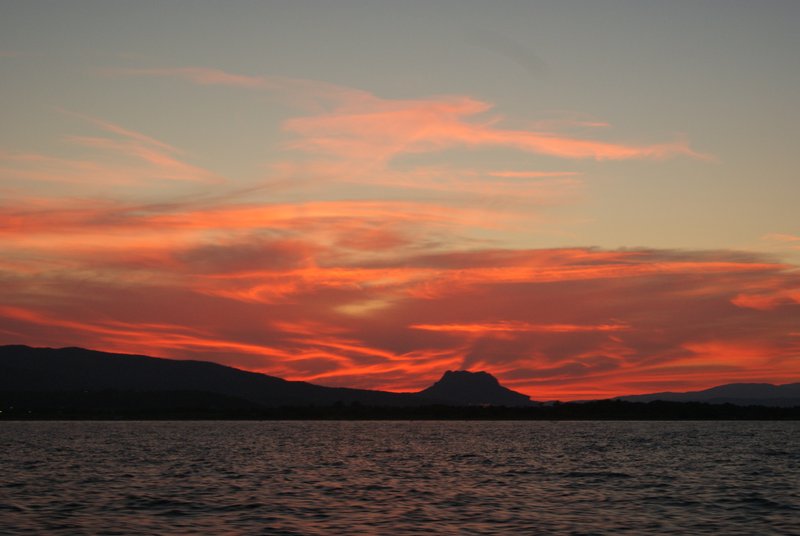 Red dawn from the middle of the sea, with a clud over a montain