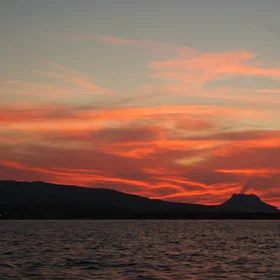 Red dawn from the middle of the sea, with a clud over a montain