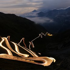 Moving lights at night on mountain road at Stelvio Pass by Roberta Paranunzio