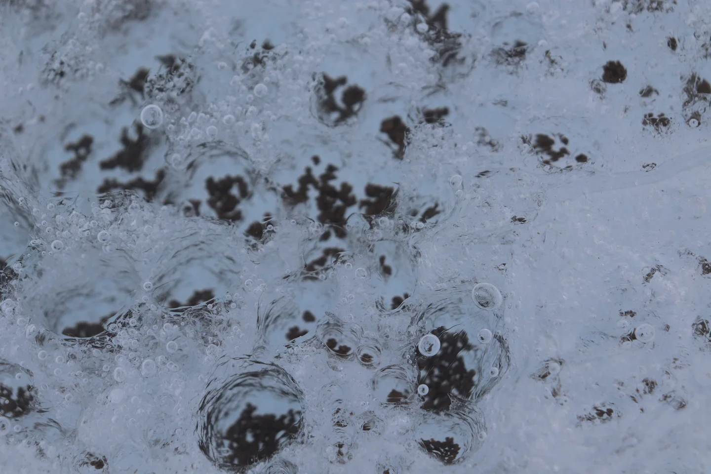 Icy melt channels by black gravel