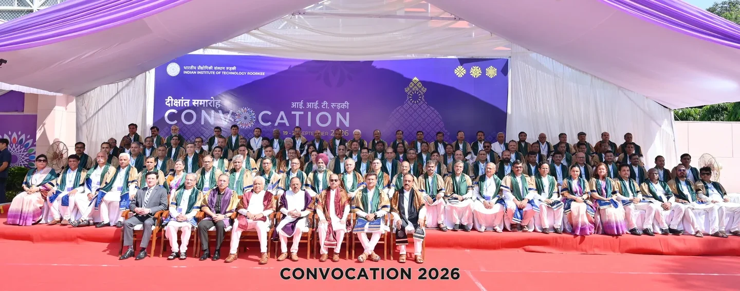 Group of formally dressed individuals sitting on stage at a convocation event in 2026.